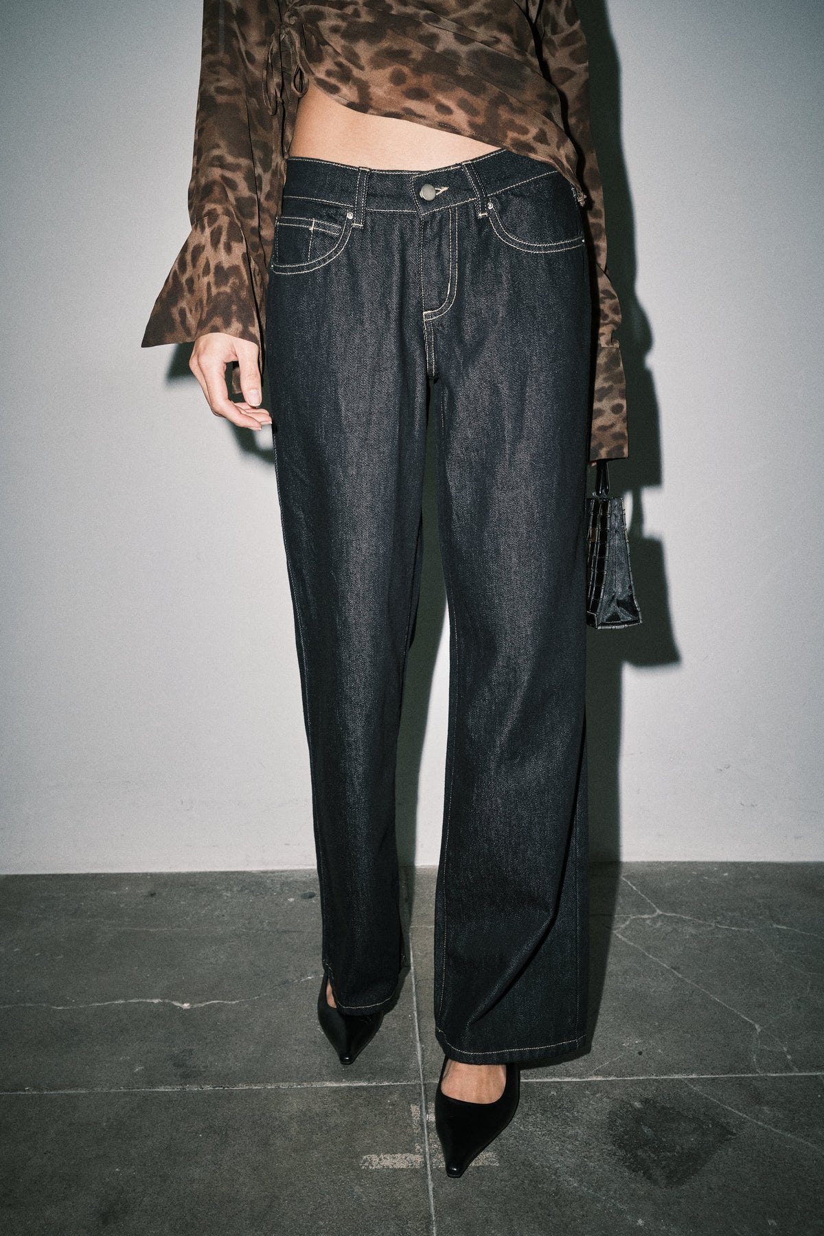 Close-up of dark wash wide leg jeans showing button closure, front pockets and contrast stitching