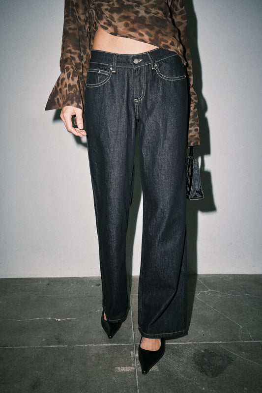 Close-up of dark wash wide leg jeans showing button closure, front pockets and contrast stitching