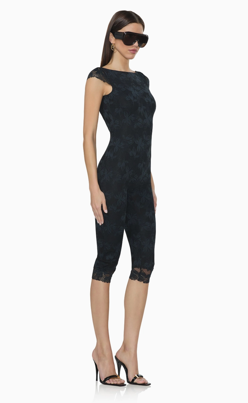 Side view of black lace capri catsuit showcasing the body-hugging silhouette, delicate floral pattern, and cropped leg length.
