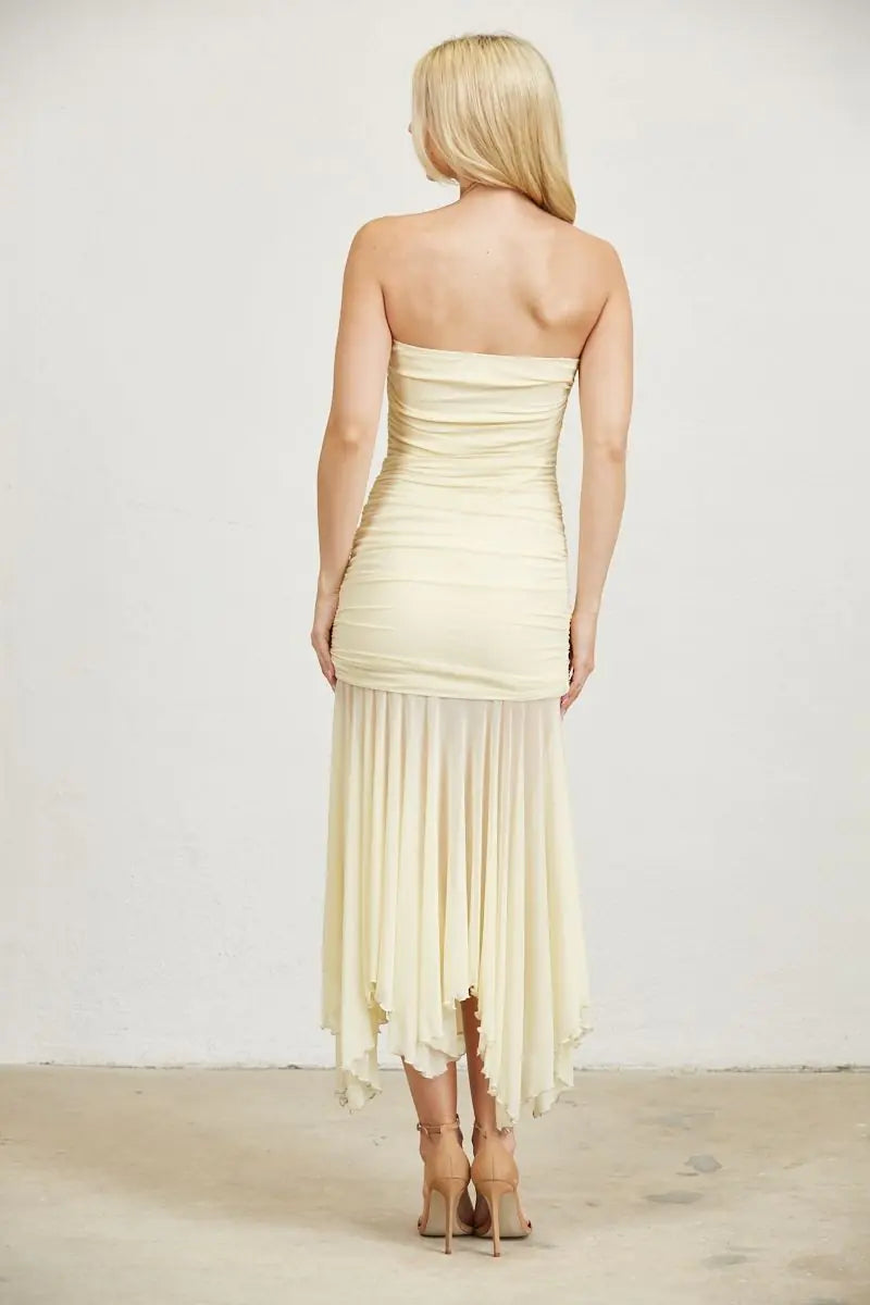 Back view of butter yellow strapless maxi dress highlighting the ruched silhouette, soft mesh fabric, and flowing handkerchief hemline.