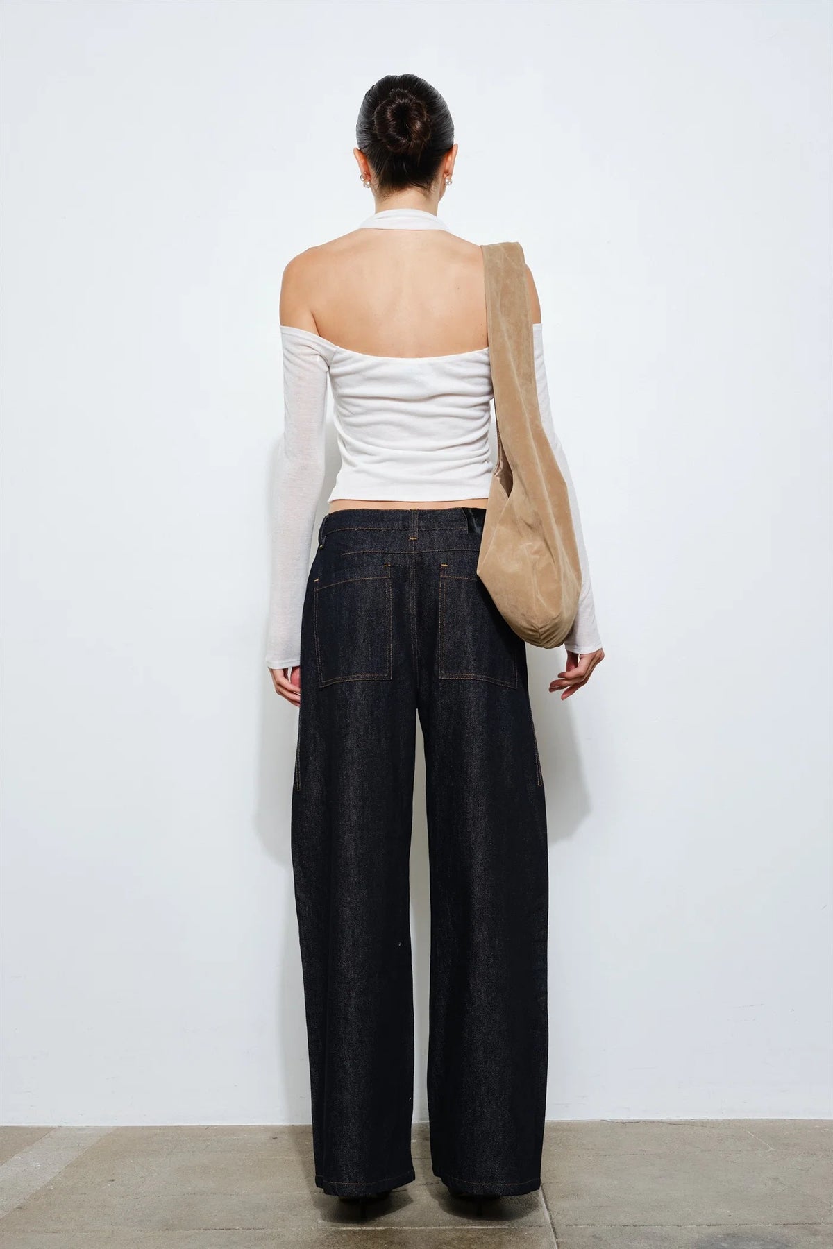 Back view of a white long sleeve cold shoulder top showing the halter neck strap, low-cut back and cropped hem