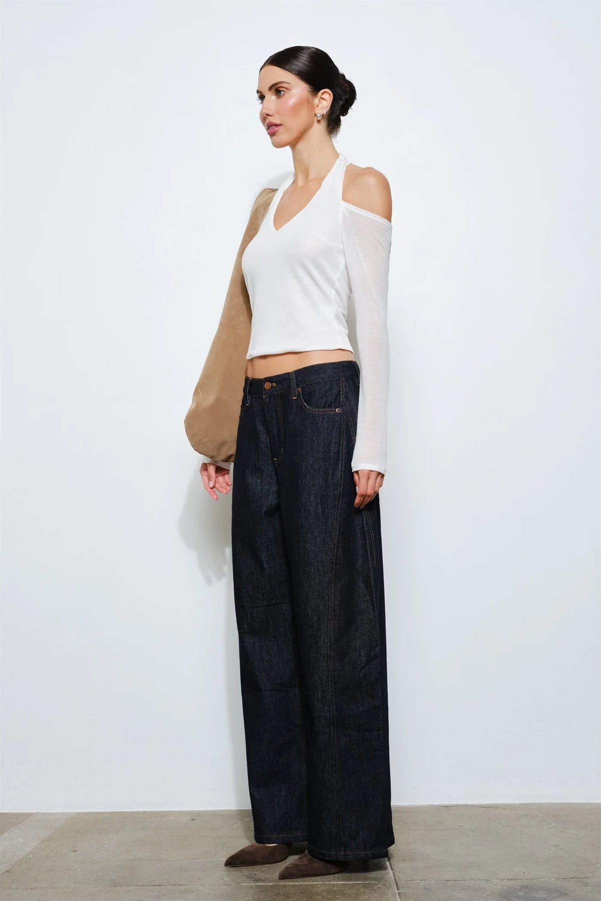Side view of a white cropped halter top showing the open shoulder, long sleeve and fitted silhouette