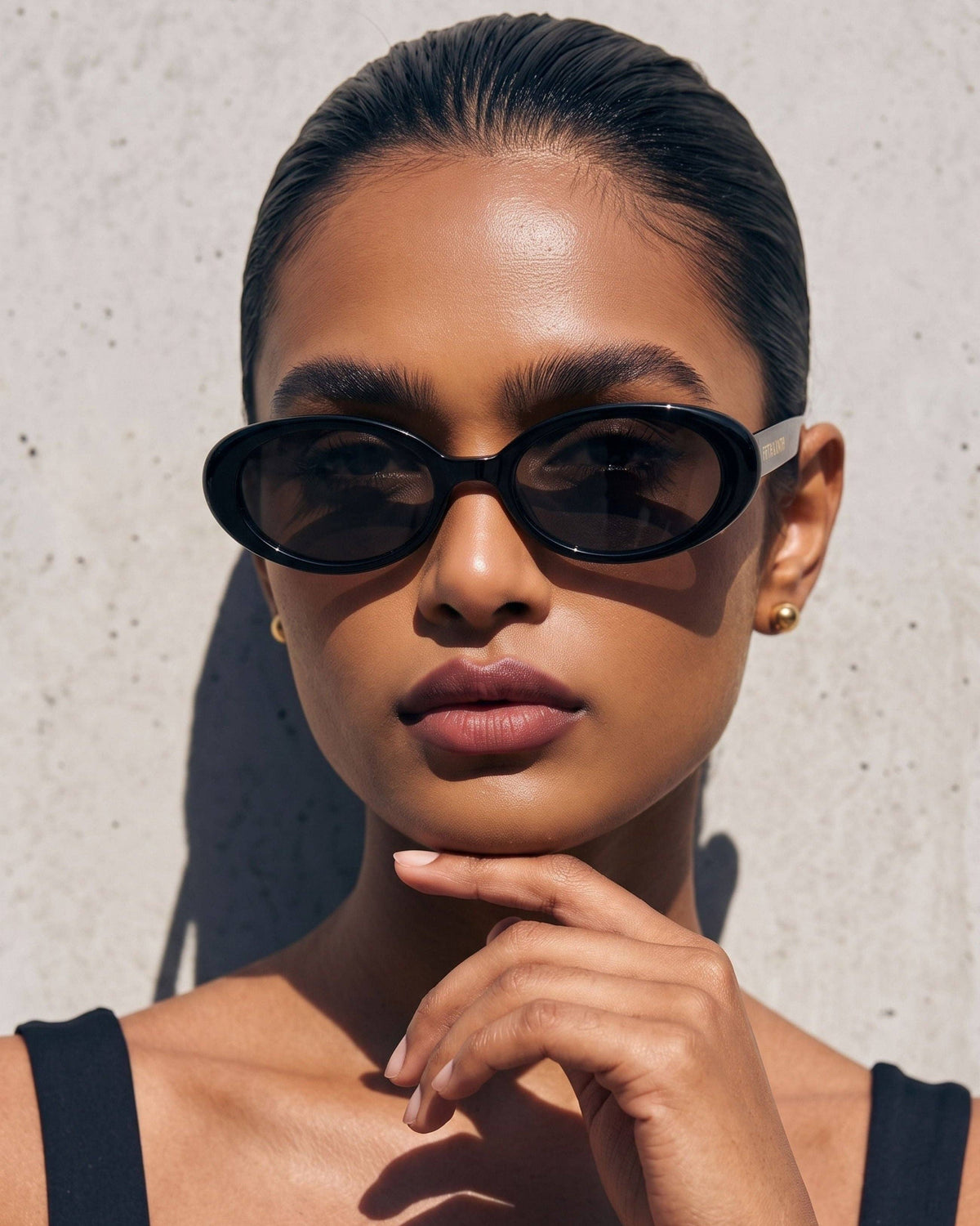 Model wearing black oval polarized sunglasses with dark lenses, showcasing the narrow frame and minimalist retro-inspired silhouette.