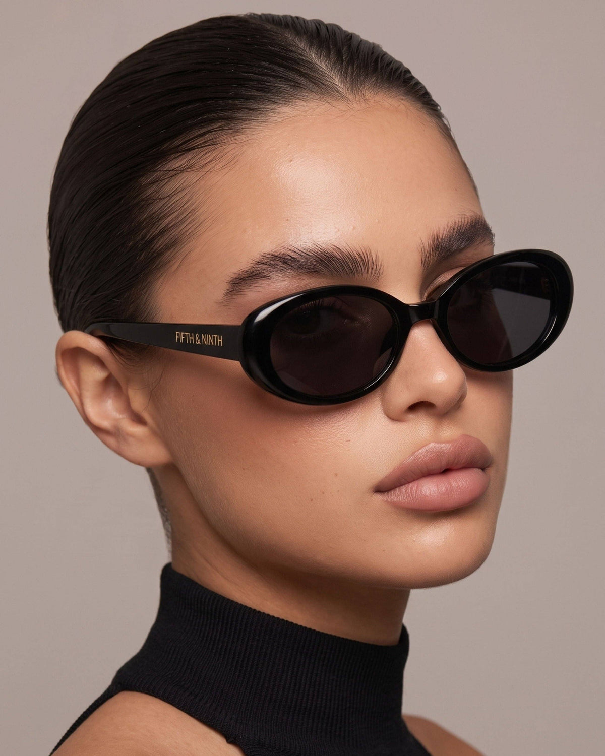 Fashion model styling black oval polarized sunglasses, highlighting the sleek all-black design and petite oval shape.