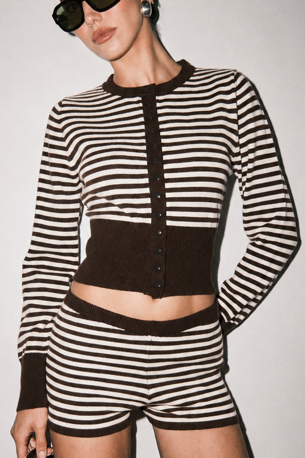 Close-up of brown and white striped cropped knit cardigan showing button-front closure, contrasting brown ribbed trim, and knit texture.